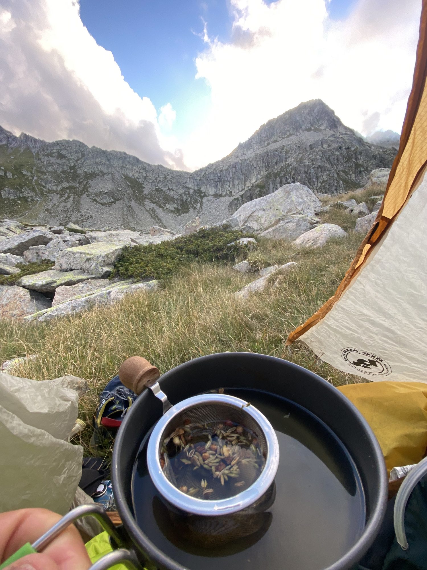 Morning herbal tea brewing inside a tent overlooking mountains